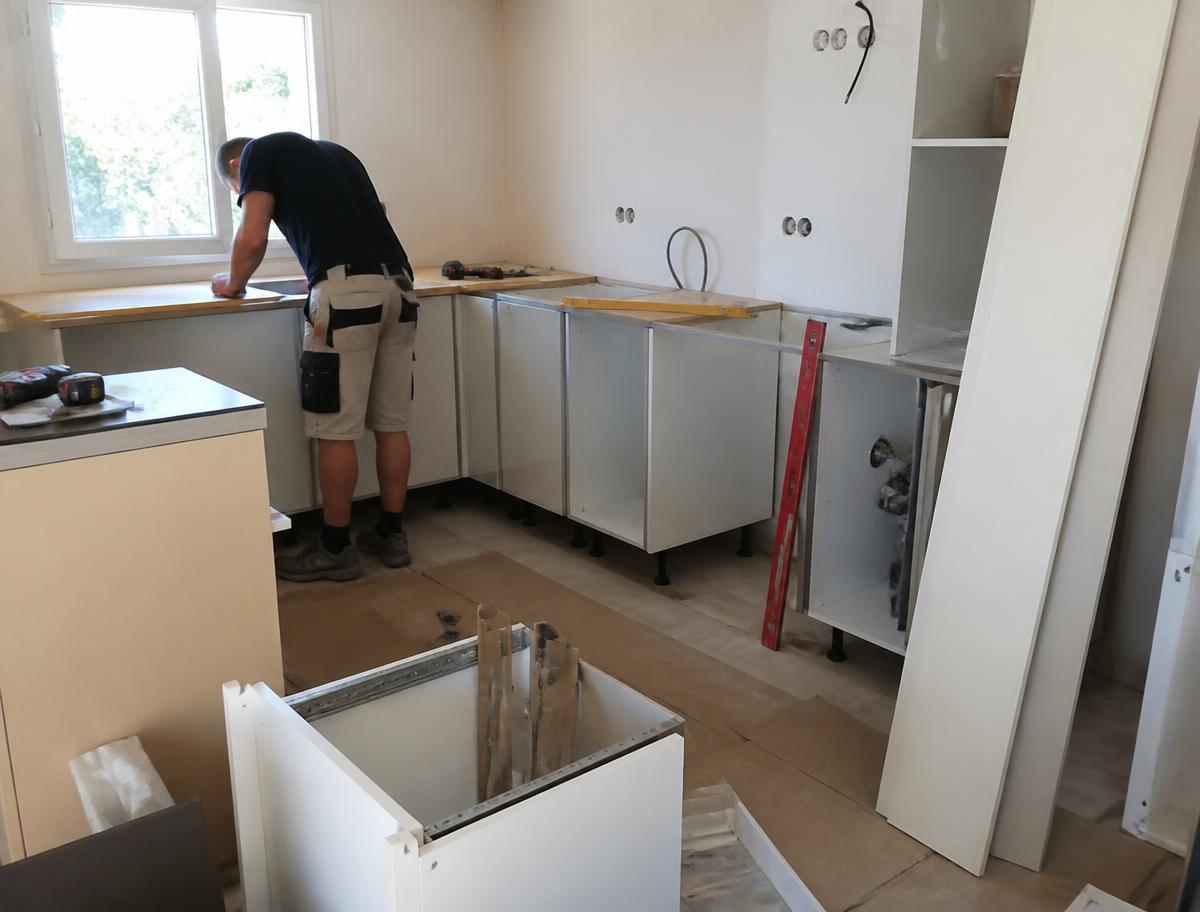 Artisan installant une cuisine dans la maison d'un particulier
